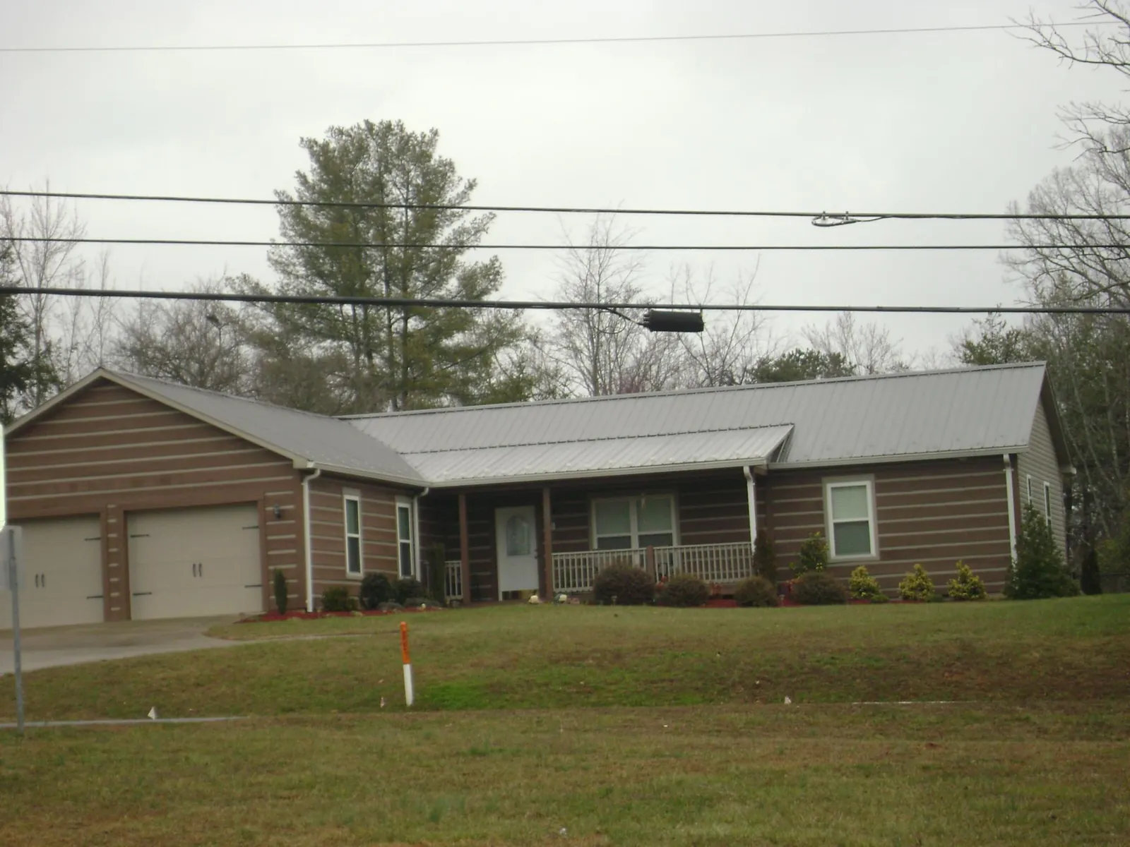 Gray metal roof on a log sided ranch home with a front porch in Red Rock