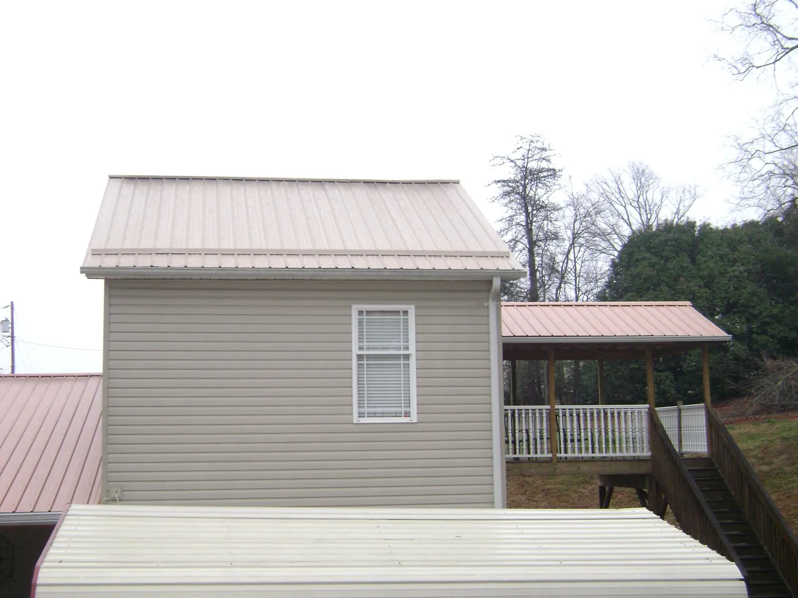 Tan metal roofs on a two story addition and attached porch, from a Roof Replacement job in Red Rock